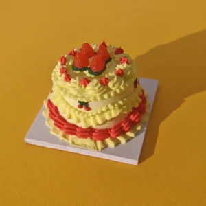 DIY miniature strawberry cream cake made from yellow and red air dry clay on a yellow background.