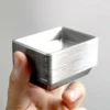 silver-plastic-mini-trays-stack Stack of 25 silver-tone plastic miniature trays held in hand for scale