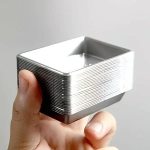 Stack of 25 silver-tone plastic miniature trays held in hand for scale