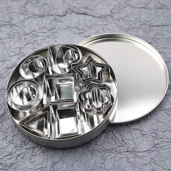 1772347519371--1670440062 A 24-piece set of mini stainless steel clay cutters in various geometric shapes shown next to a pink ruler for scale. The set includes nesting hearts, stars, flowers, and circles for miniature food crafting.